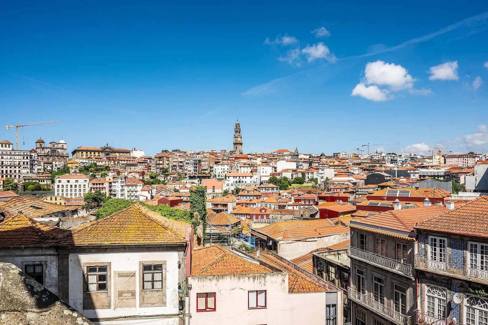Terracotta rooftops and a bell tower beneath a blue sky in Porto, photographed in 2026